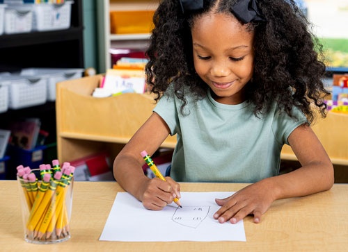 Young girl drawing a house